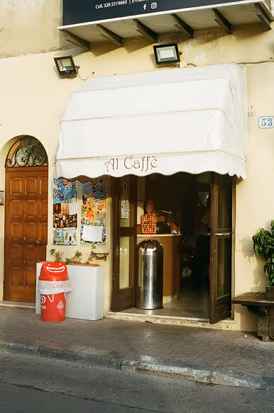 Credit: Death to Stock. Small Italian cafe entrance with white awning that reads 'Al Caffè' and open wooden doors on a street.