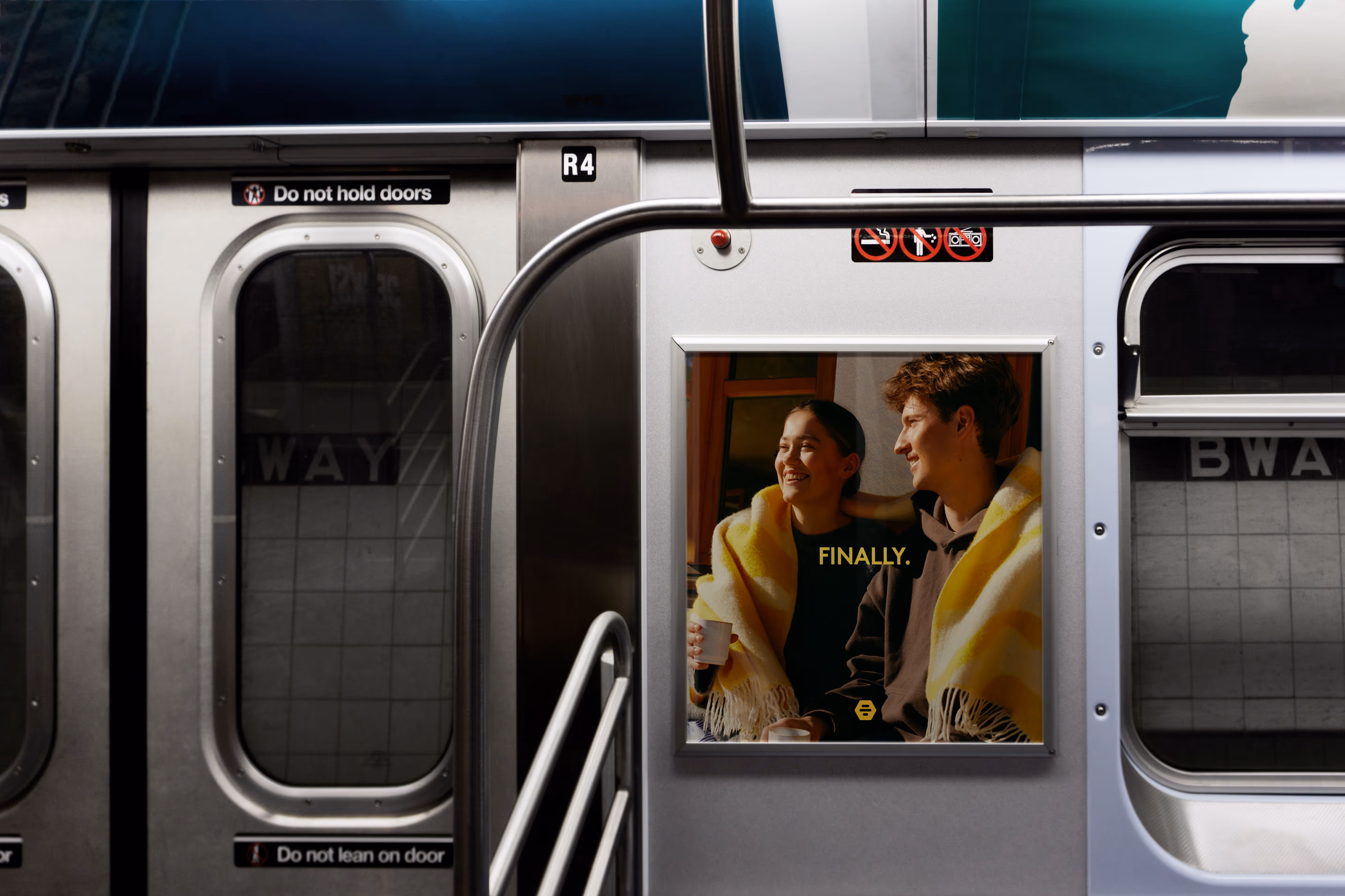 Credit: Maison Mockups. A subway car interior with an ad showing a smiling couple wrapped in yellow blankets and text saying 'FINALLY.'