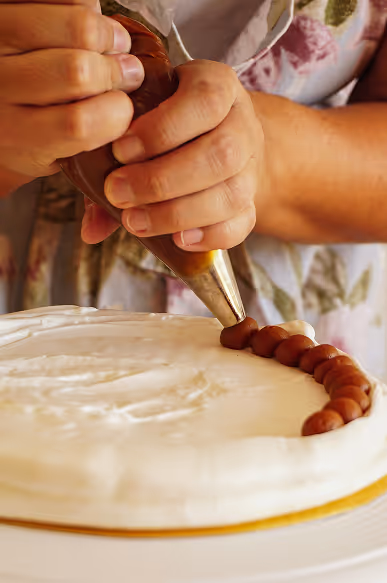 Credit Istock: Frederico Faccipieri
Woman icing white cake with red icing.
