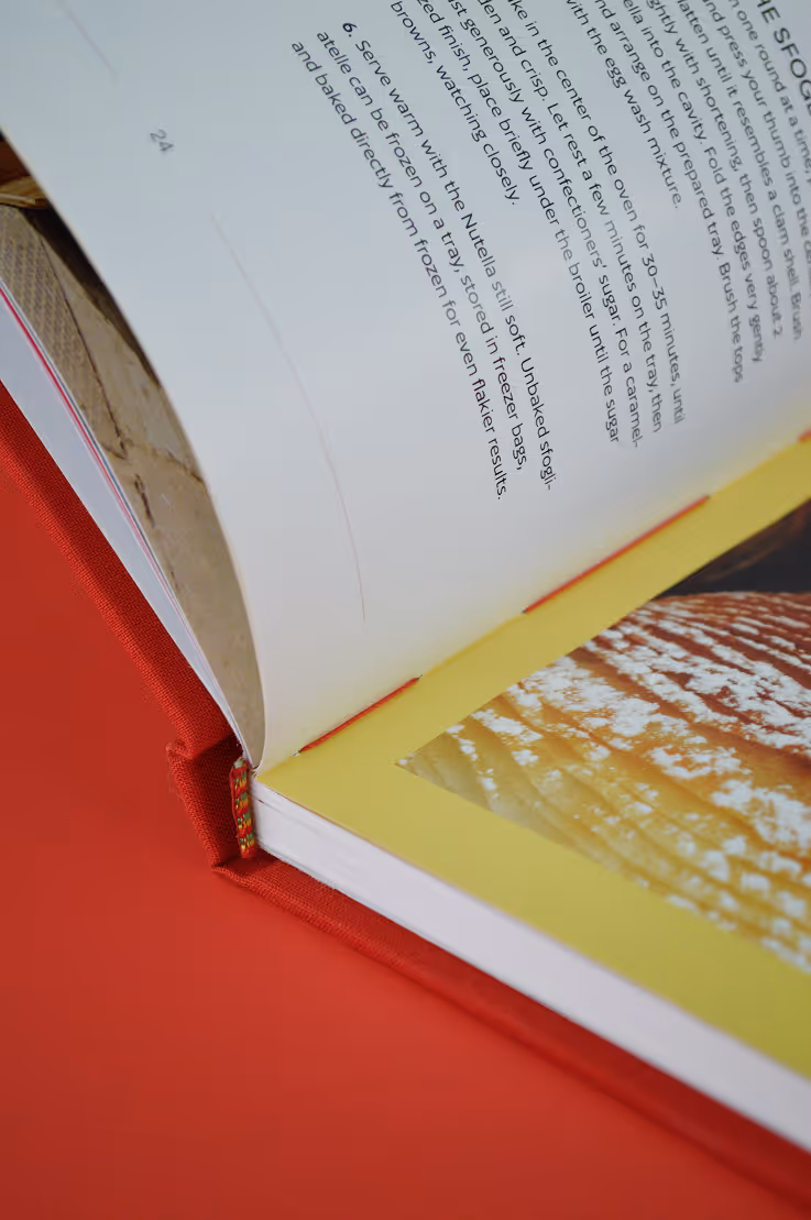 Credit: Emilia Piazza. Close-up of open cookbook showing a page with text and a photo of a baked pastry.