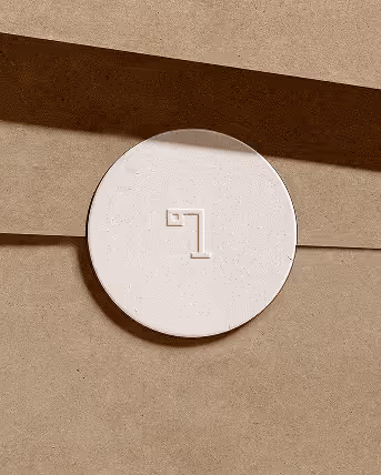 Credit Chat GPT
Rounded white sticker with the minimalist lamp logo embossed on the center, stuck on a brown paper