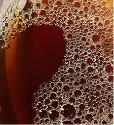 Credit: ChatGPT
Close-up of bubbles on the surface of dark amber tea, in a glass.
