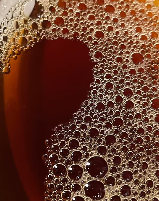 Credit: ChatGPT
Close-up of bubbles on the surface of dark amber tea, in a glass.